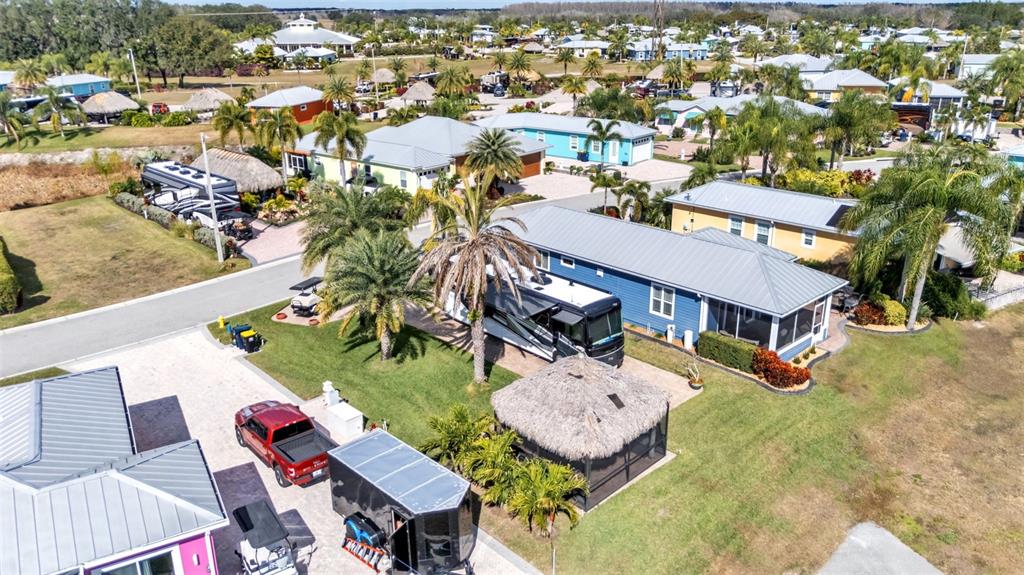 An aerial view shows a blue house with a metal roof, an RV, and a tiki hut — 3268 FISH HAWK DRIVE, POLK CITY, FL