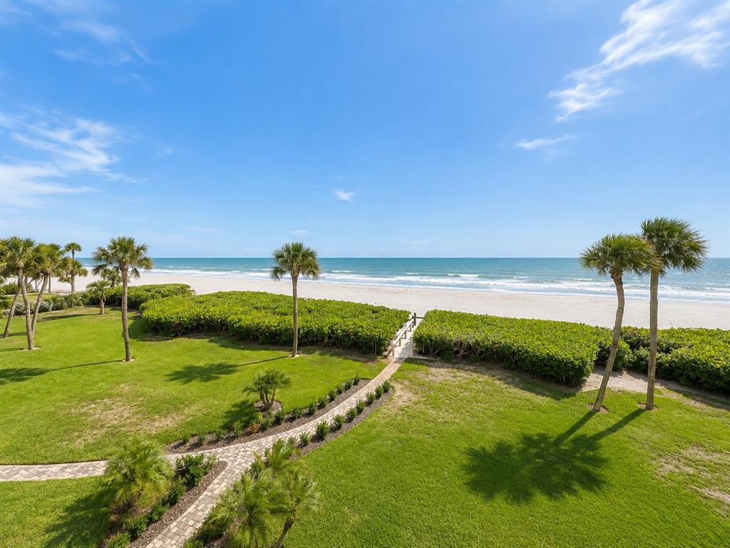 A grassy lawn with palm trees leads to a sandy beach and the ocean — 2675 GULF OF MEXICO DRIVE UNIT 203, LONGBOAT KEY, FL