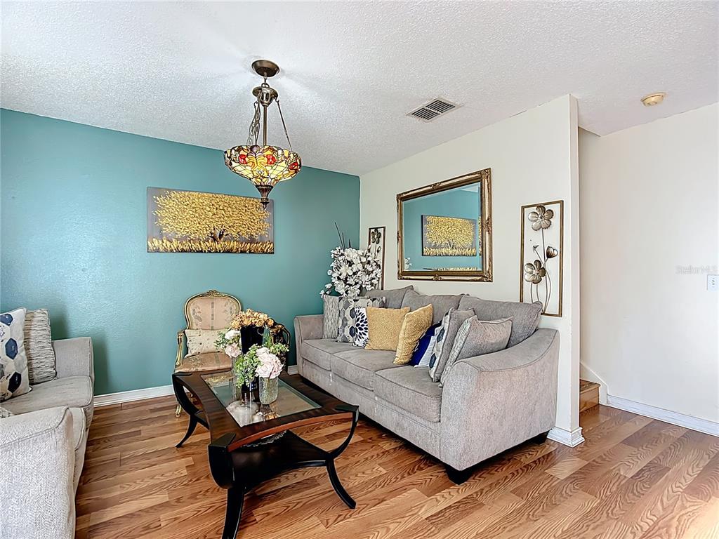 A living room features a teal accent wall, a gray sofa, and a glass-topped coffee table — 5009 STRADA DRIVE, WINTER HAVEN, FL