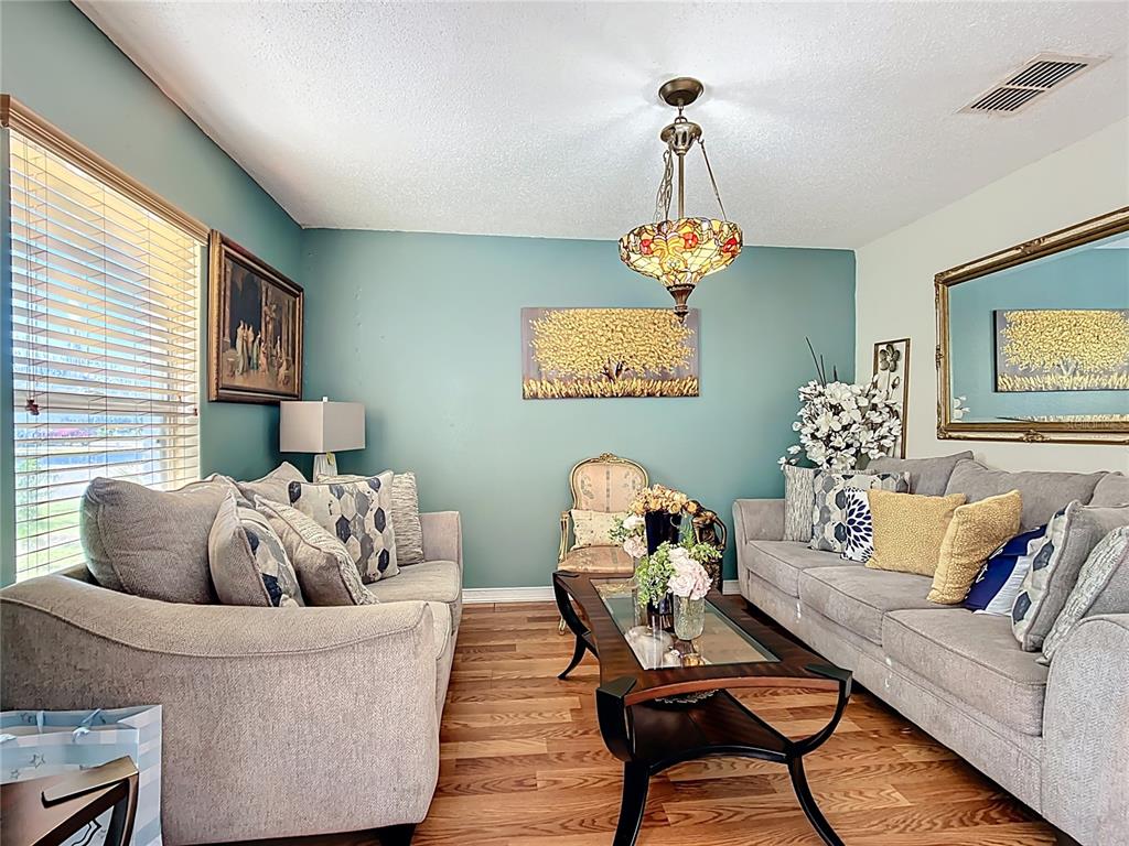 A living room features two gray sofas, a glass-topped coffee table, and teal walls — 5009 STRADA DRIVE, WINTER HAVEN, FL