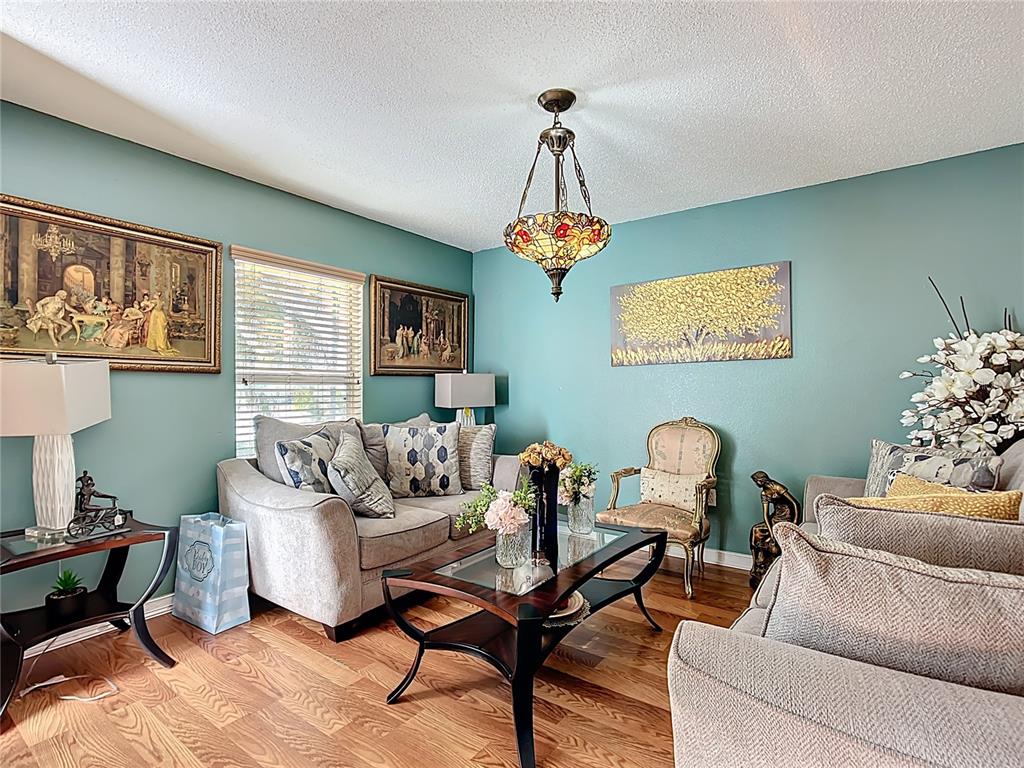 A living room features teal walls, a stained-glass chandelier, two sofas, and hardwood flooring — 5009 STRADA DRIVE, WINTER HAVEN, FL