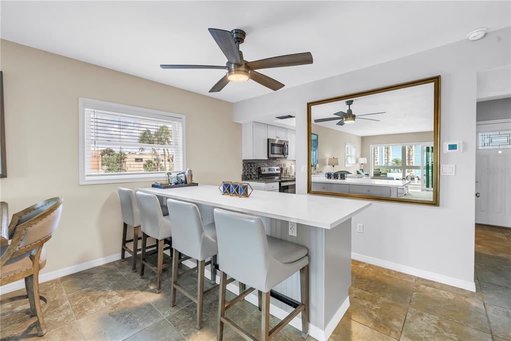 A kitchen island with bar seating sits in a room featuring a large wall mirror — 6201 2ND STREET E UNIT 82, ST PETE BEACH, FL