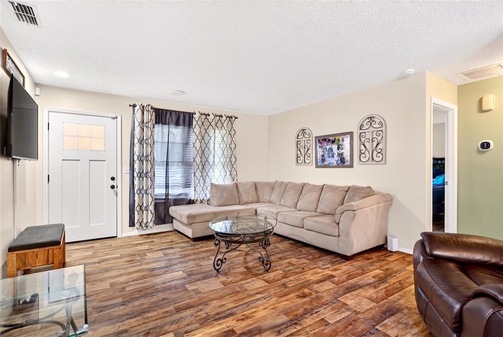 A living room features a beige sectional sofa, a glass coffee table, and wood flooring — 27 CEDAR TRACE, OCALA, FL
