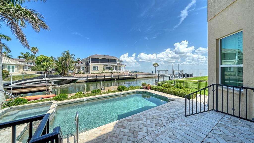 A backyard swimming pool overlooks a canal with a boat lift and a large house — 657 HALYARD LANE, LONGBOAT KEY, FL