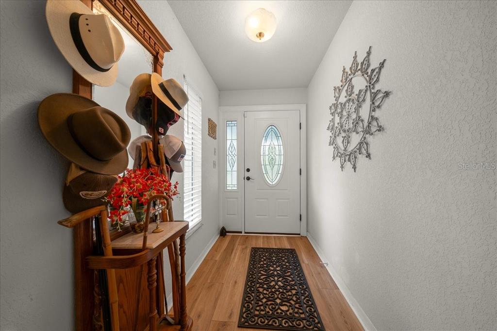 An entryway features a wood-framed mirror, a hat rack, and a front door with glass — 2222 SW 167TH PLACE, OCALA, FL