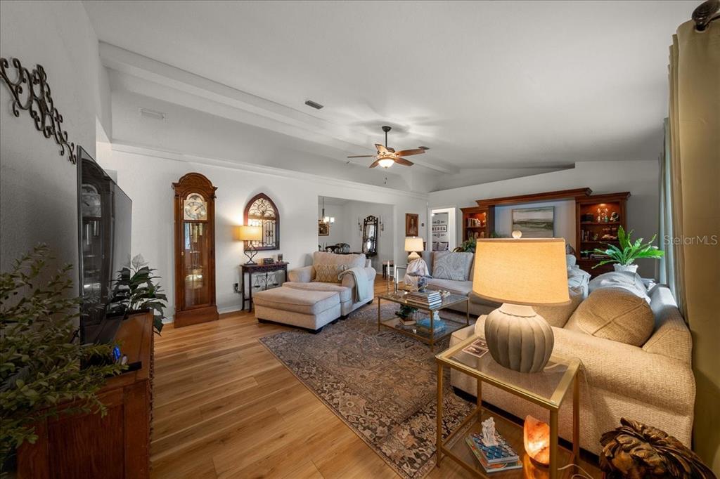 A living room features light wood flooring, a vaulted ceiling, and a large area rug — 2222 SW 167TH PLACE, OCALA, FL