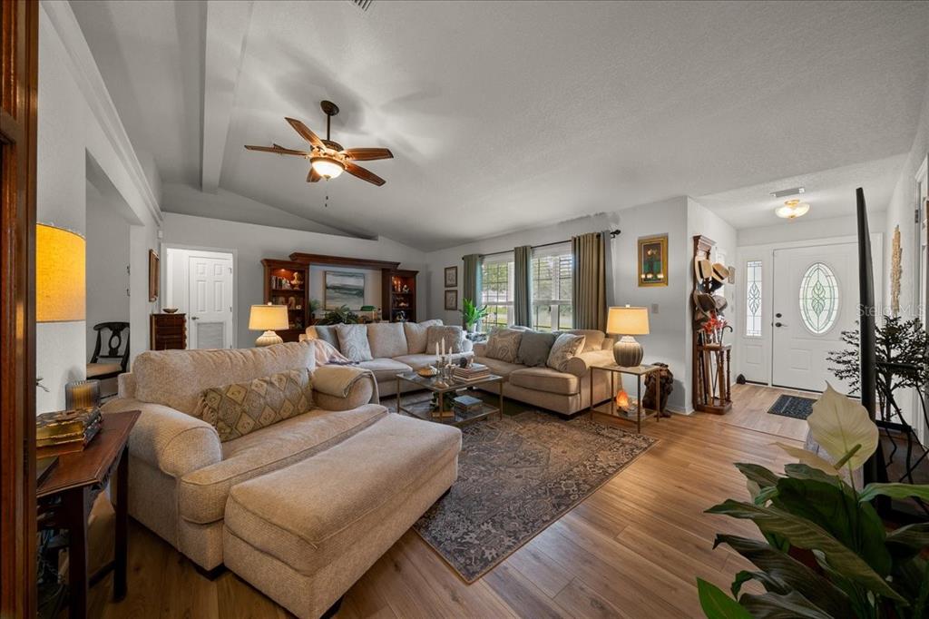 A living room features a vaulted ceiling, light wood flooring, and a large sectional sofa — 2222 SW 167TH PLACE, OCALA, FL
