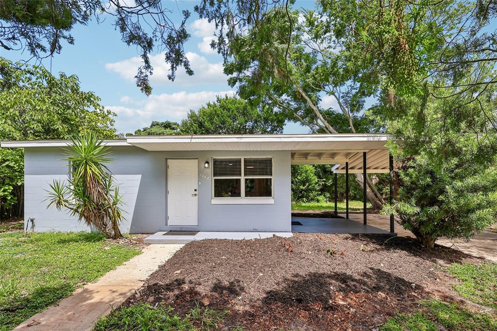 A light gray, single-story house with a white door, a window, and an attached carport — 1062 BARCLAY DRIVE, COCOA, FL