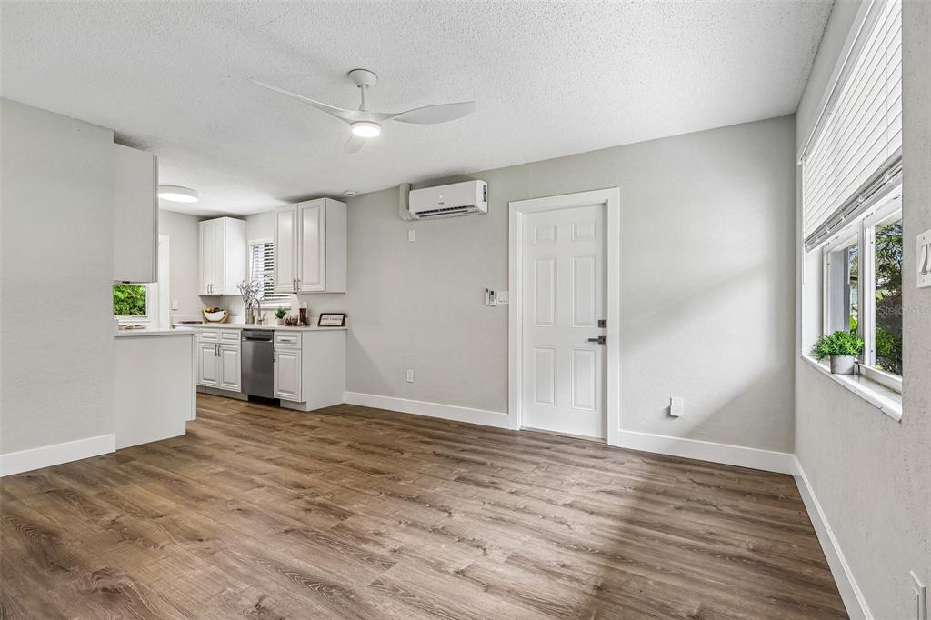 A kitchen and dining area with white cabinets, wood-look flooring, and a wall-mounted air conditioner — 1062 BARCLAY DRIVE, COCOA, FL