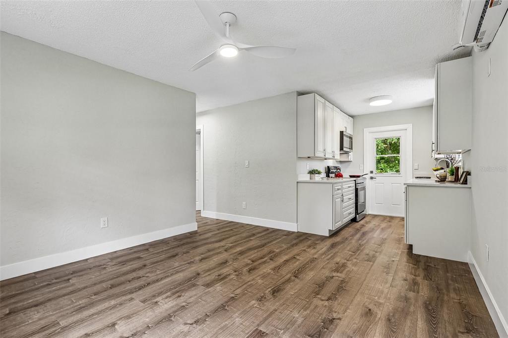 A kitchen and dining area with light gray walls, white cabinets, and wood-look flooring — 1062 BARCLAY DRIVE, COCOA, FL