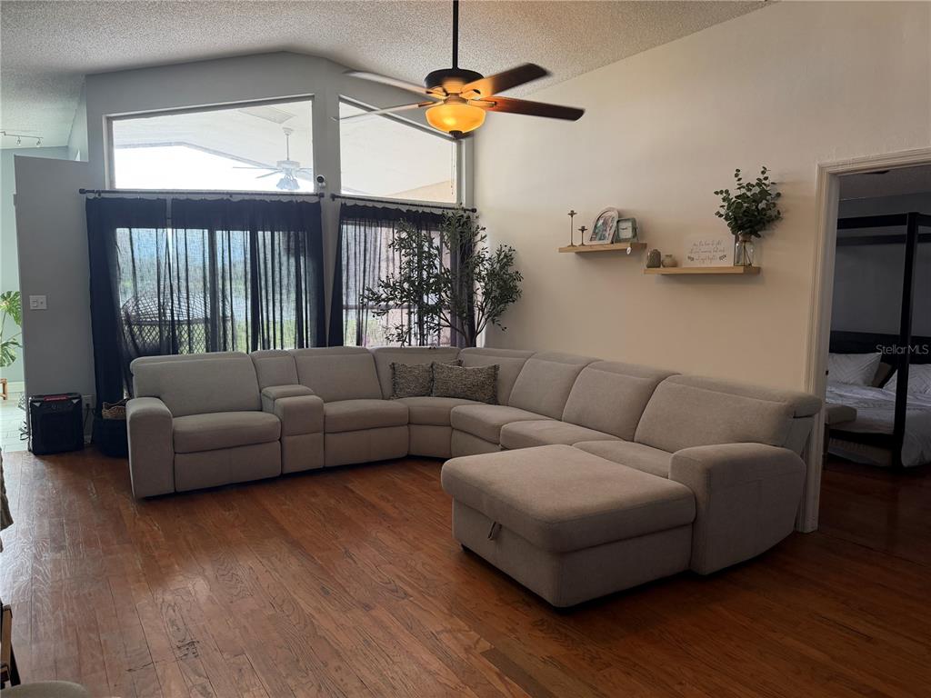 A living room features a large gray sectional sofa, hardwood floors, and high vaulted ceilings — 3236 KOVAL COURT, ORLANDO, FL