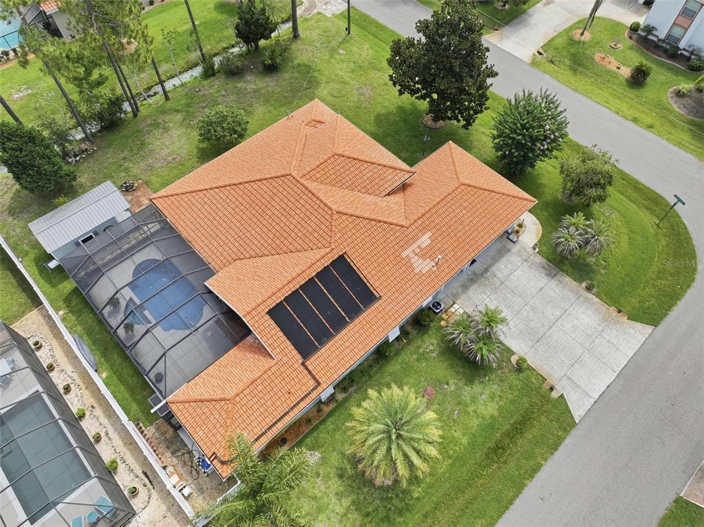 An aerial view shows a house with a tiled roof, pool enclosure, and solar panels — 20 EVANSTON LANE, PALM COAST, FL