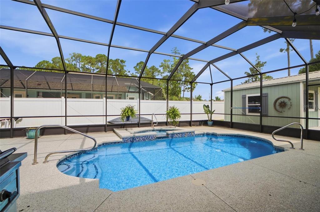 A screened-in patio features a swimming pool with an attached spa and concrete decking — 20 EVANSTON LANE, PALM COAST, FL