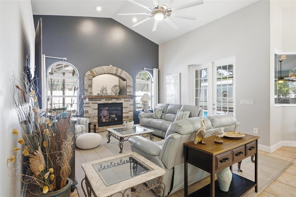 A living room features a stone fireplace, vaulted ceiling, and light gray leather furniture — 20 EVANSTON LANE, PALM COAST, FL