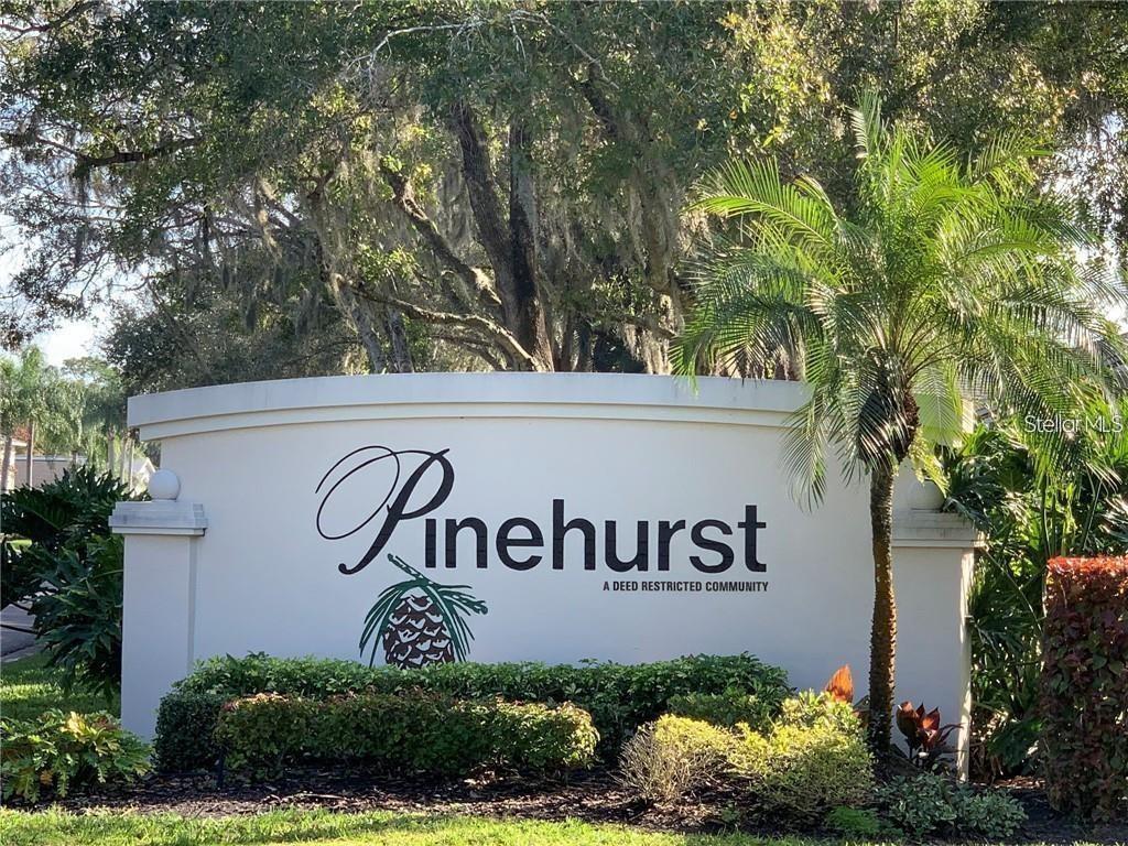 A curved white monument sign displays the name Pinehurst in front of trees and landscaping — 7287 ELEANOR CIRCLE UNIT 15, SARASOTA, FL