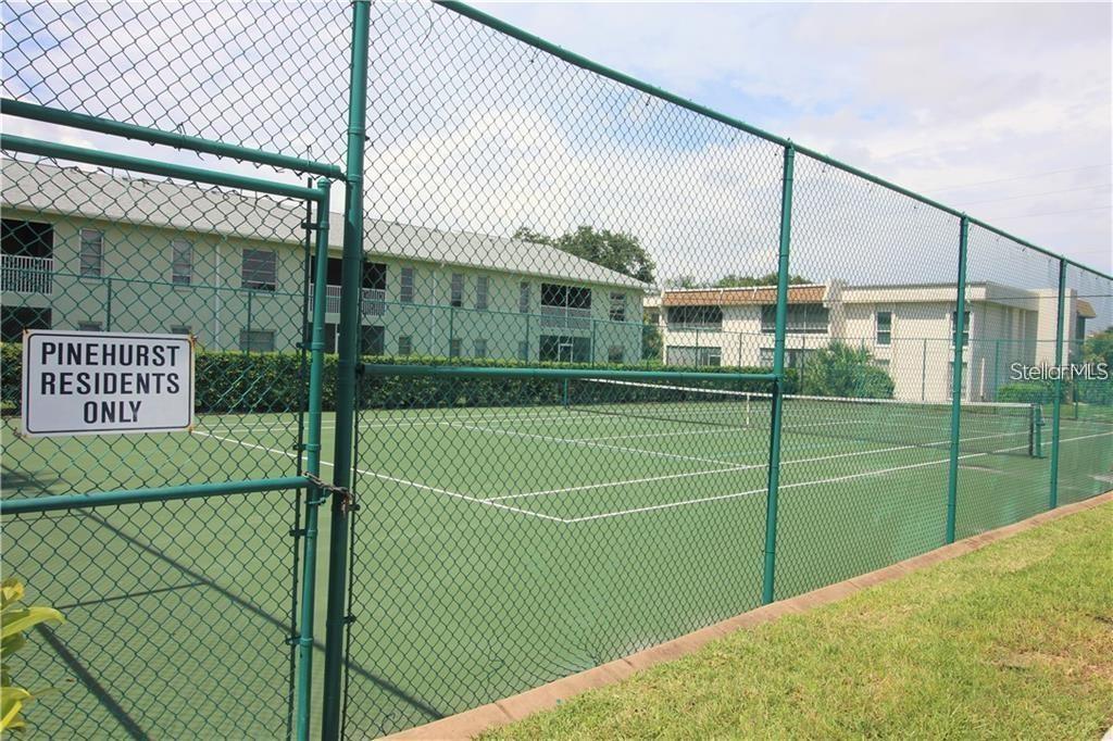 A fenced-in tennis court sits in front of two multi-story apartment buildings — 7287 ELEANOR CIRCLE UNIT 15, SARASOTA, FL
