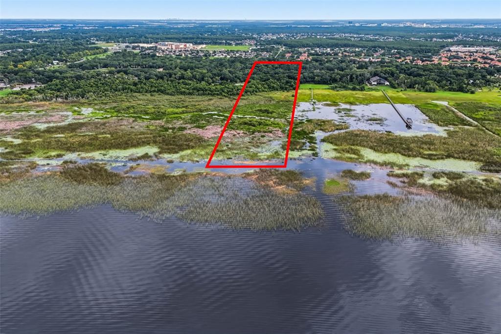 An aerial view shows a red-outlined vacant lot bordering a lake and marshland — 2794 HOLIDAY WOODS DRIVE, KISSIMMEE, FL