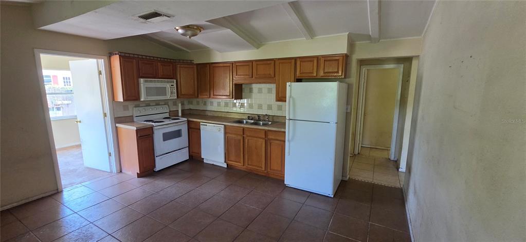 A kitchen with wood cabinets, white appliances, and brown tile flooring — 8944 MARIGOLD DRIVE, NEW PORT RICHEY, FL