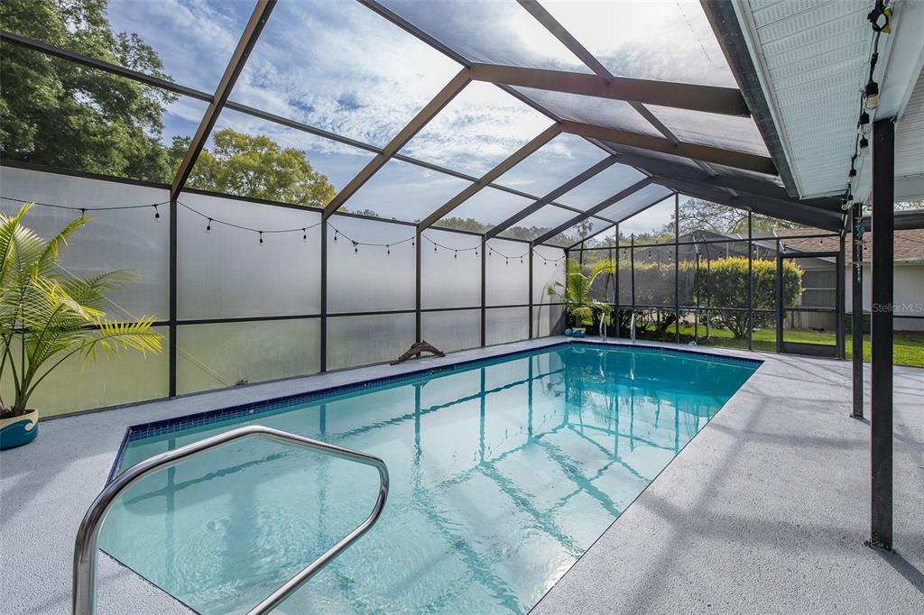 A rectangular swimming pool is enclosed by a screened-in lanai with a concrete deck — 13316 BRIGHAM LANE, HUDSON, FL