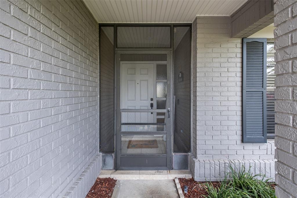 A front entryway features a grey brick exterior, a storm door, and a white front door — 13316 BRIGHAM LANE, HUDSON, FL
