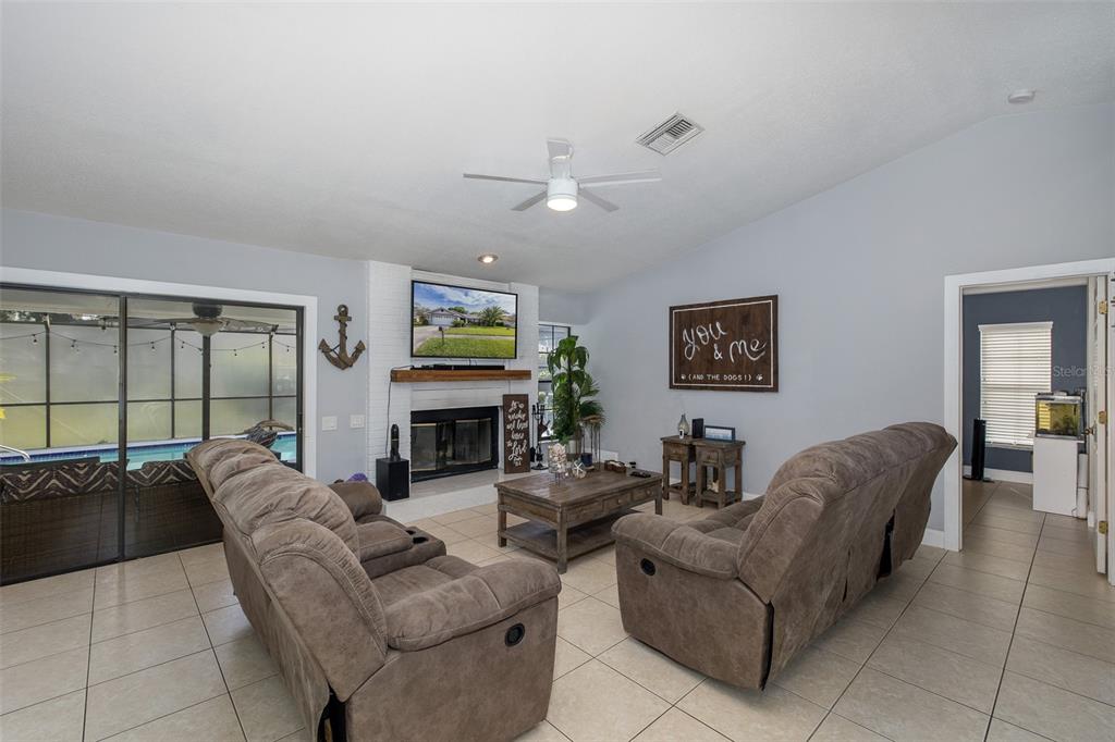 A living room features a white brick fireplace, tile flooring, and two brown reclining sofas — 13316 BRIGHAM LANE, HUDSON, FL