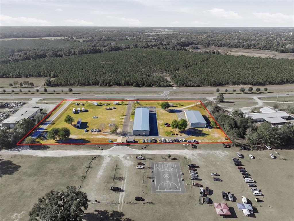 An aerial view shows two metal buildings on a large, fenced-in grassy lot — 20761 NE HIGHWAY 27, WILLISTON, FL