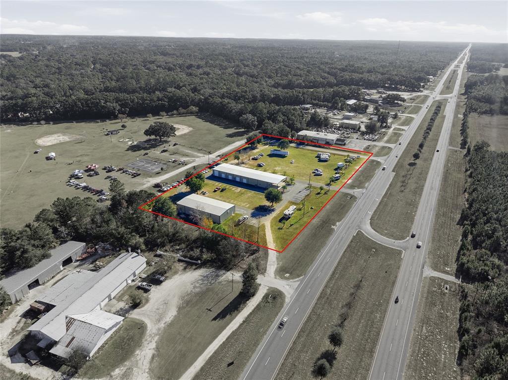An aerial view shows two industrial buildings on a large lot adjacent to a highway — 20761 NE HIGHWAY 27, WILLISTON, FL