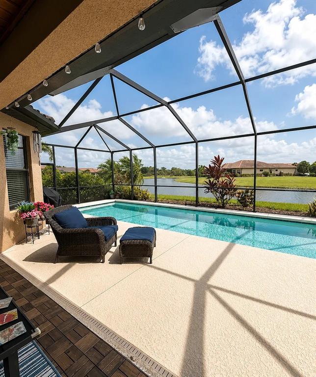 A screened-in patio features a swimming pool, wicker furniture, and a view of a lake — 10319 SAINT FRANCIS TERRACE, PALMETTO, FL