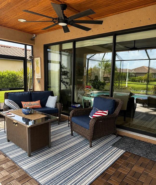 A covered patio features a ceiling fan, wicker furniture, and a view of a pool — 10319 SAINT FRANCIS TERRACE, PALMETTO, FL