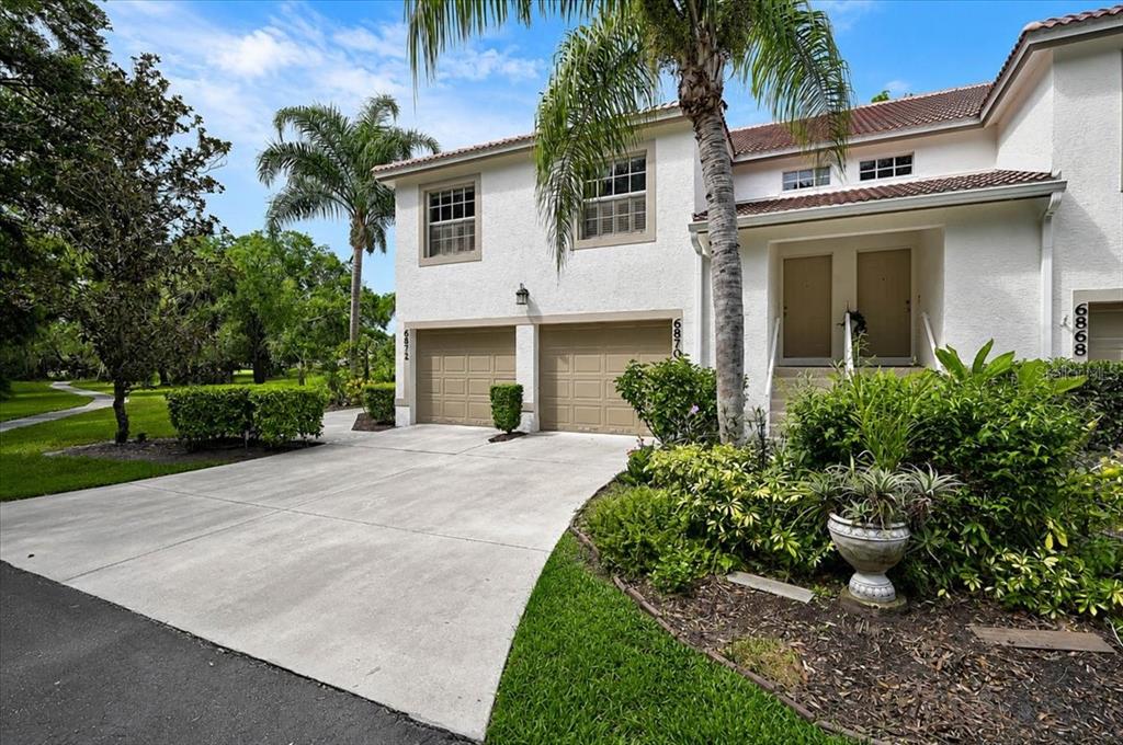A two-story residential building features two beige garage doors and a landscaped front yard — 6870 FAIRVIEW TERRACE, BRADENTON, FL