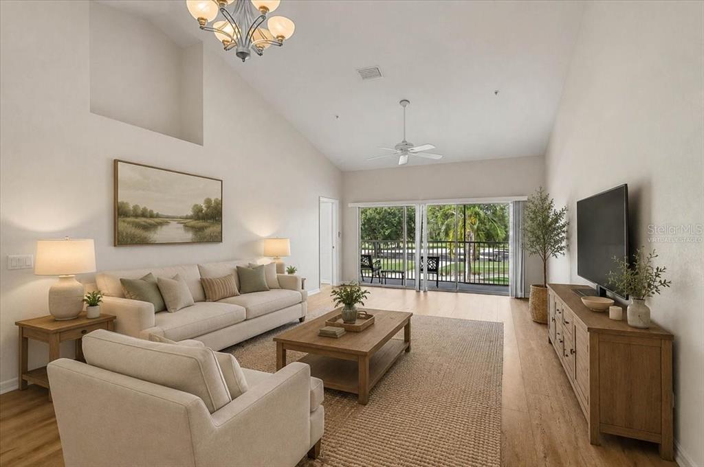 A living room features a vaulted ceiling, neutral furniture, a wooden coffee table, and sliding doors — 6870 FAIRVIEW TERRACE, BRADENTON, FL