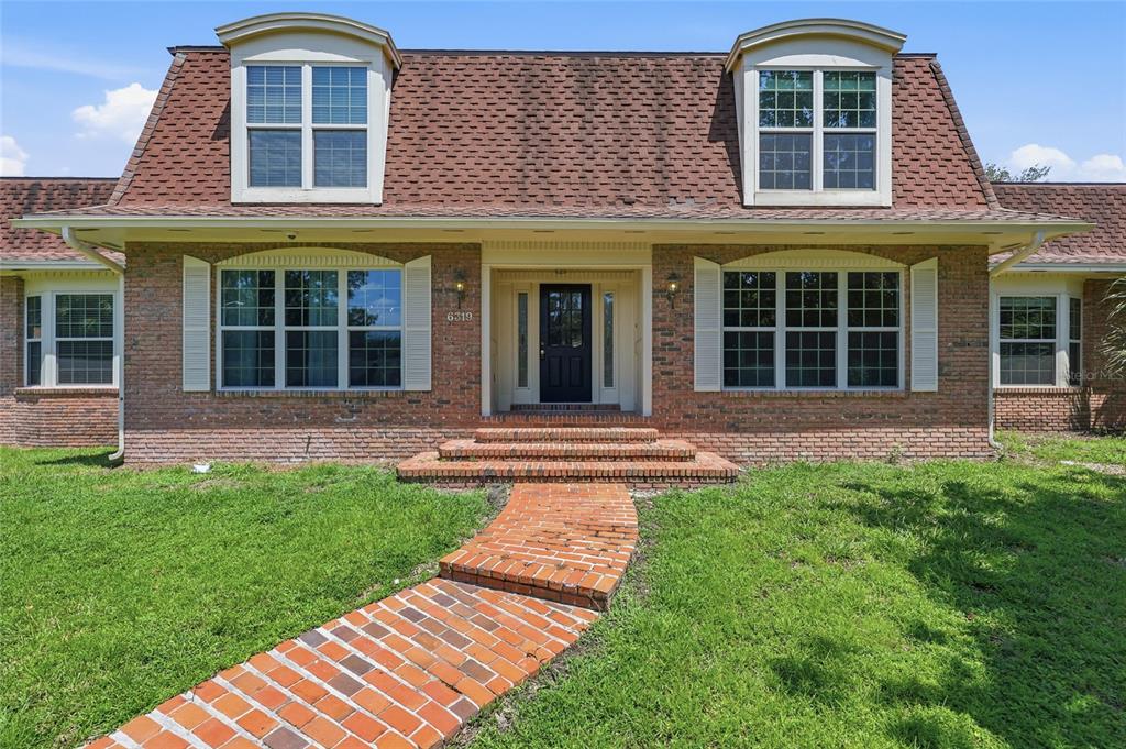 A brick house with a gambrel roof, two dormer windows, and a brick walkway — 6319 SW 37TH WAY, GAINESVILLE, FL