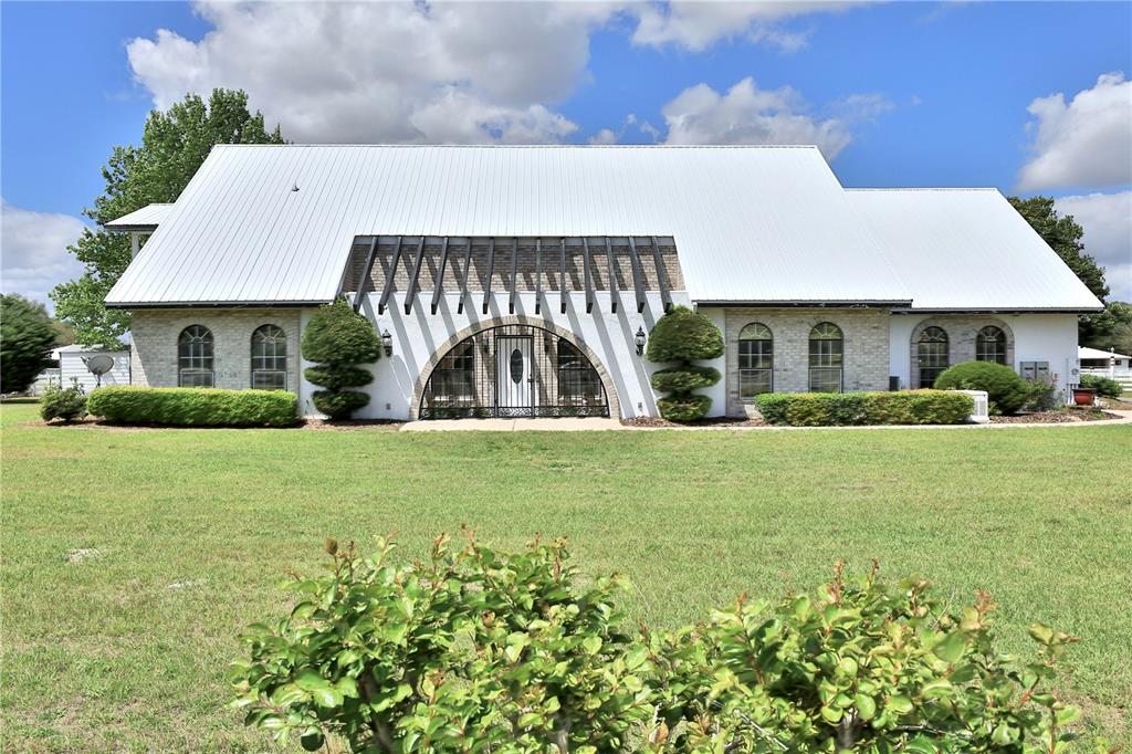 A single-story house with a white metal roof, brick exterior, and a central arched entryway — 4450 SE 216TH AVENUE UNIT Option 2, MORRISTON, FL