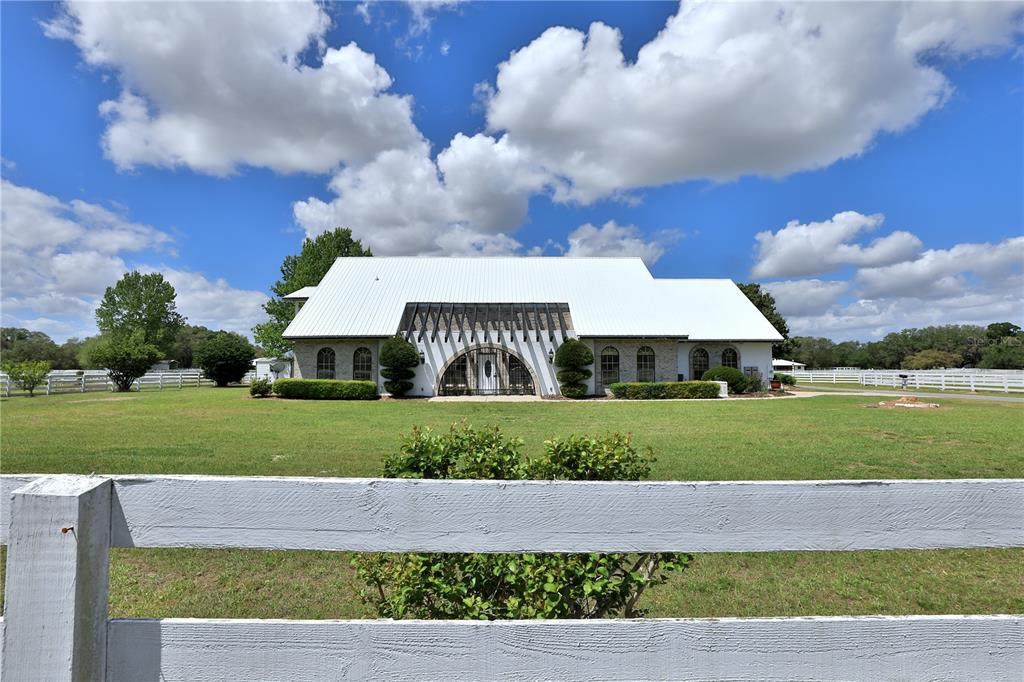 A white house with a metal roof and a large arched entryway sits on grass — 4450 SE 216TH AVENUE UNIT Option 2, MORRISTON, FL