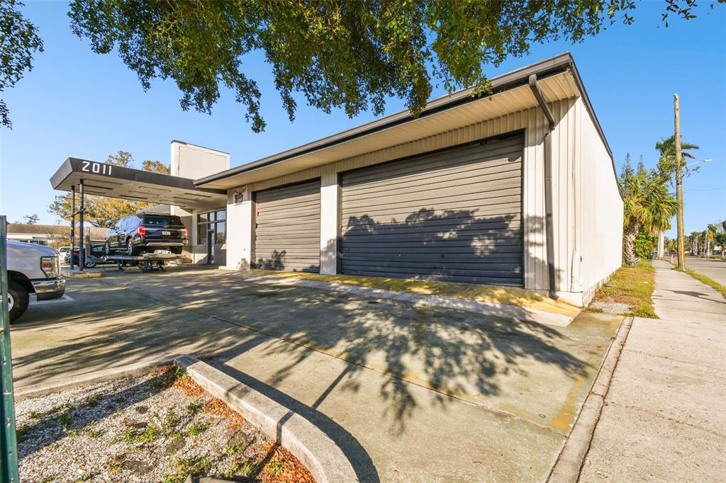 An exterior view of a commercial building with two roll-up garage doors and a canopy — 2011 9TH STREET W, BRADENTON, FL