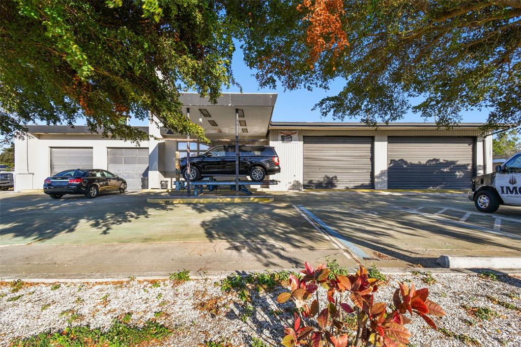 An exterior view of a commercial building with multiple garage bays and a vehicle lift — 2011 9TH STREET W, BRADENTON, FL