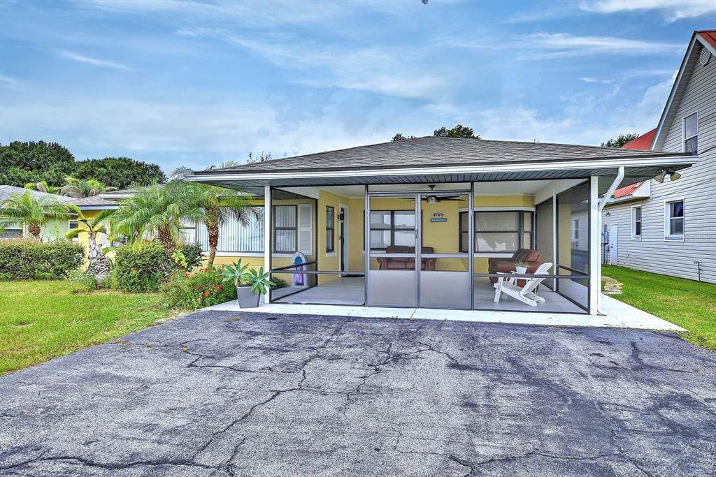 A house exterior features a large screened-in front porch and a cracked asphalt driveway — 4160 LAKEVIEW DRIVE, SEBRING, FL