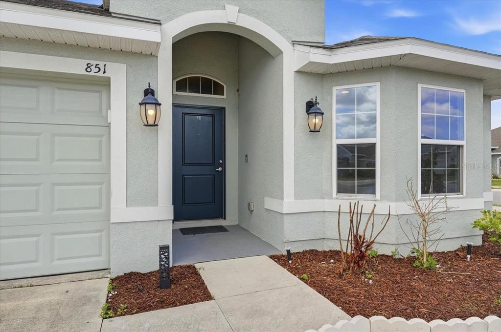 A light-colored house exterior features a dark blue front door and a garage entrance — 851 VIENNA DRIVE, WINTER HAVEN, FL