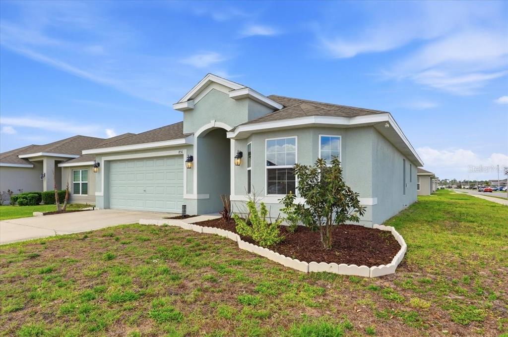 A light green single-story house with a two-car garage and a landscaped front yard — 851 VIENNA DRIVE, WINTER HAVEN, FL