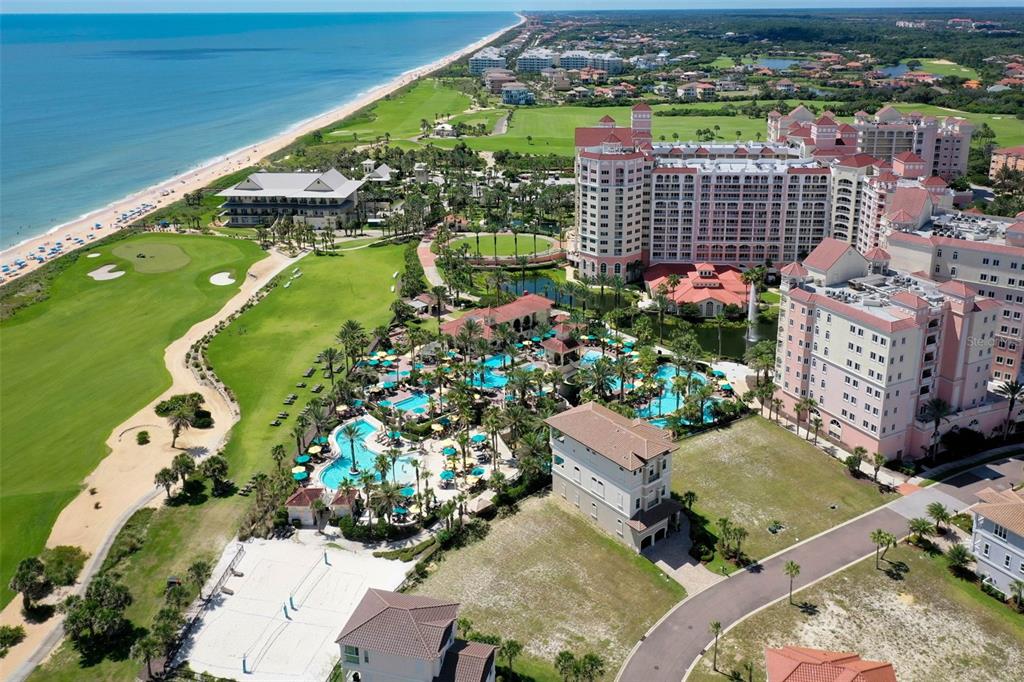 An aerial view shows a large resort hotel with pools, a golf course, and beach — 200 OCEAN CREST DRIVE UNIT 906, PALM COAST, FL