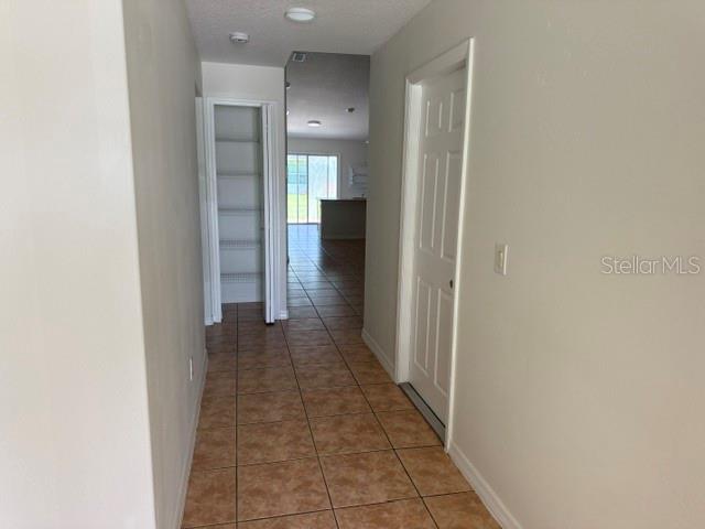 A hallway with tile flooring leads to a pantry and an open living area — 20 UNION RUN COURT, PALM COAST, FL