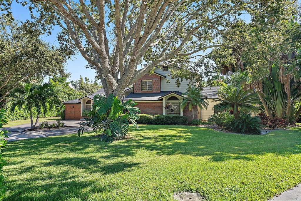 A two-story brick and siding house sits behind a large tree and green lawn — 2371 LANDINGS CIRCLE, BRADENTON, FL