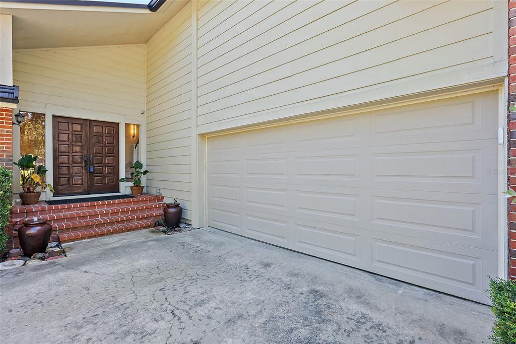 A beige house exterior features a double front door, brick steps, and a garage door — 2371 LANDINGS CIRCLE, BRADENTON, FL