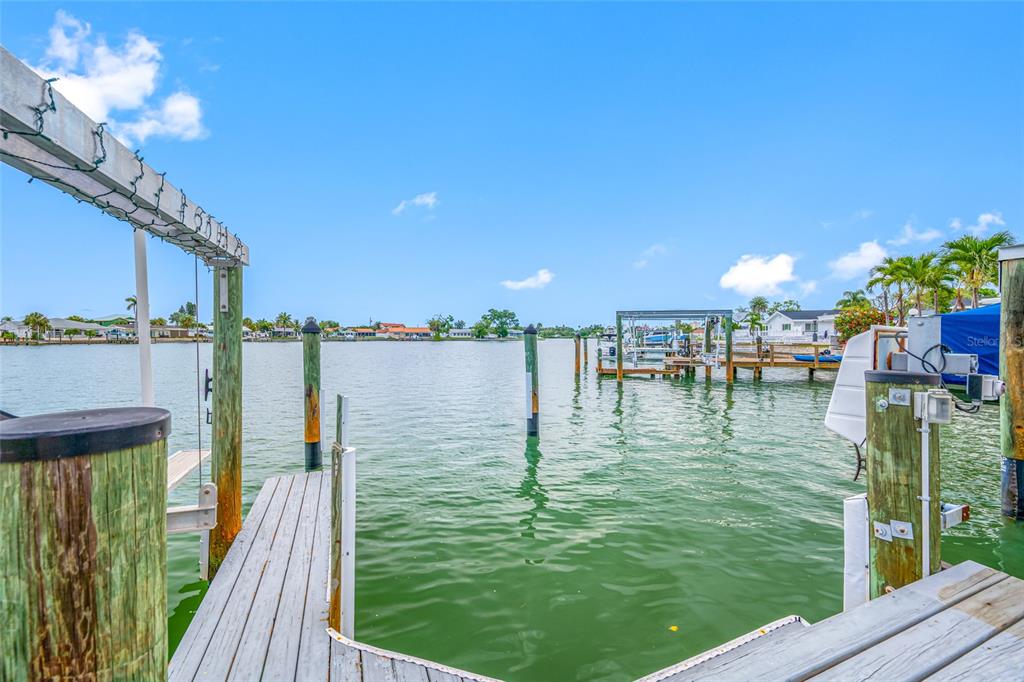 A wooden boat dock extends into a calm waterway under a clear blue sky — 560 79TH STREET S, ST PETERSBURG, FL