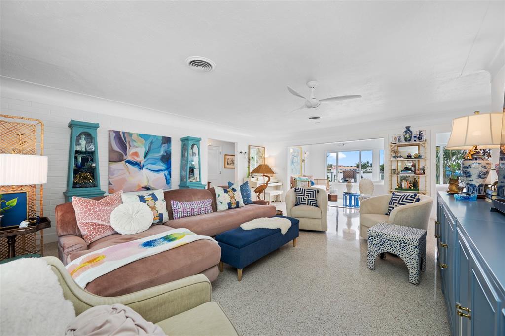 A bright living room features a large sectional sofa, blue accents, and light-colored terrazzo flooring — 560 79TH STREET S, ST PETERSBURG, FL