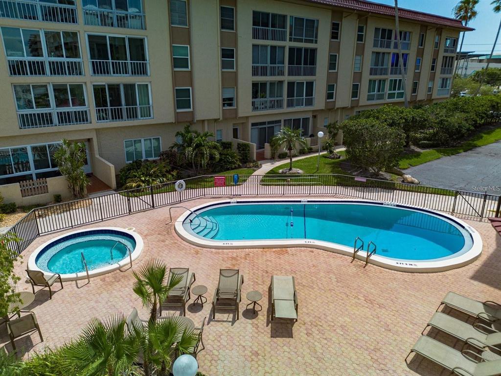 An outdoor swimming pool and hot tub are surrounded by a paved deck and building — 105 ISLAND WAY UNIT 138, CLEARWATER, FL