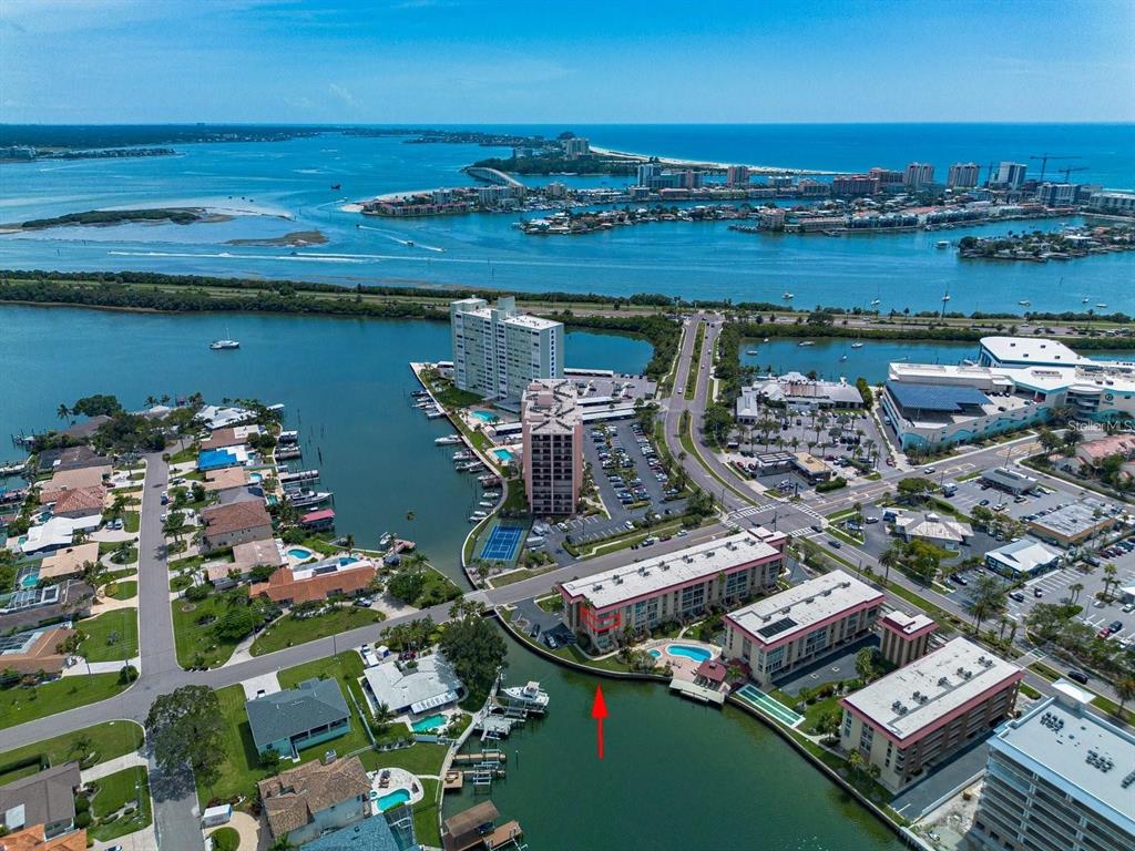 An aerial view shows a waterfront condominium complex with a pool and boat docks — 105 ISLAND WAY UNIT 138, CLEARWATER, FL