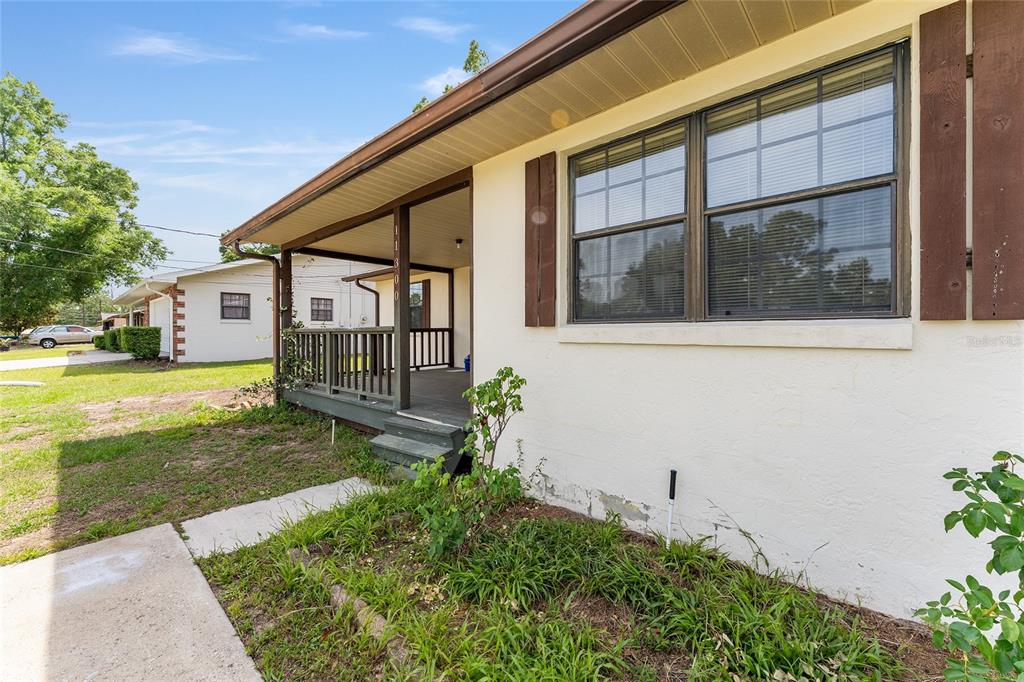 A side view of a house exterior showing a covered porch and a large window — 11300 SE 74TH AVENUE, BELLEVIEW, FL