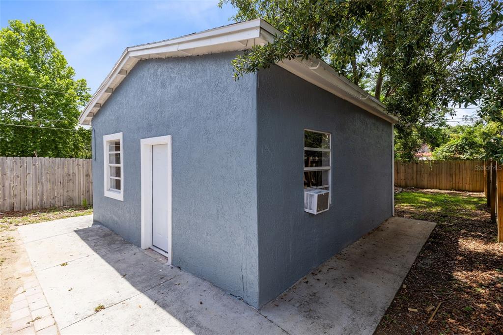 A blue stucco detached structure with a white door, two windows, and a concrete patio — 3432 HARRY STREET, APOPKA, FL