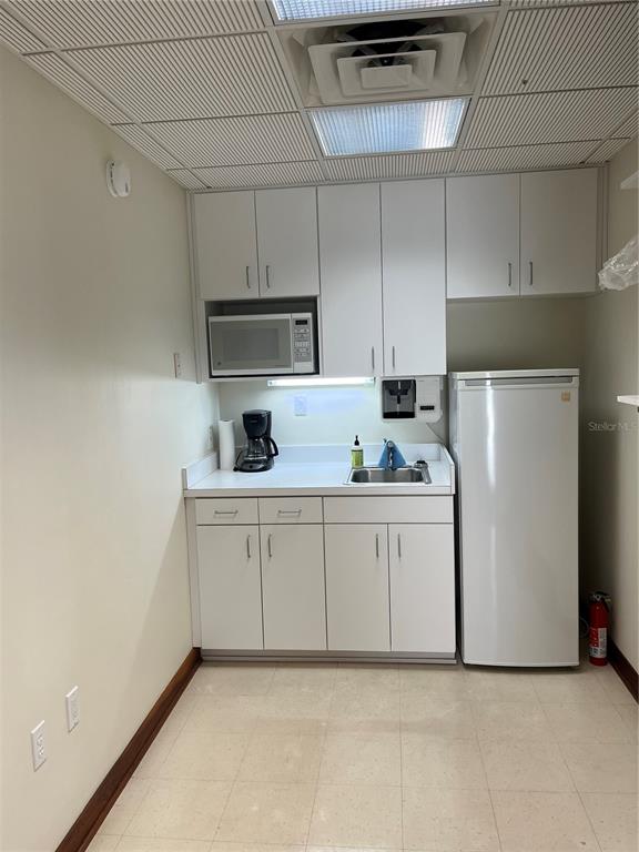 A small kitchenette features white cabinets, a microwave, a sink, and a white refrigerator — 519 NE 1ST STREET, GAINESVILLE, FL